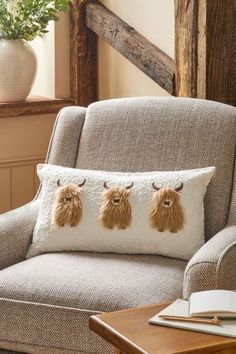 a chair with three pillows on it and a plant in the corner next to it