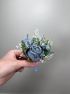 a hand holding a blue flower bouquet with baby's breath