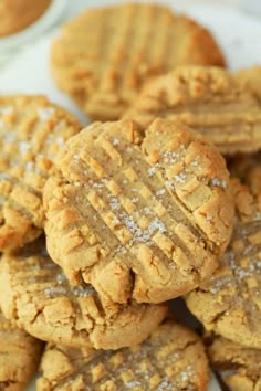 a pile of peanut butter cookies with powdered sugar on top and one cookie in the middle