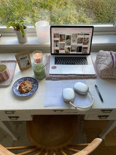 a laptop computer sitting on top of a desk next to a cup and saucer