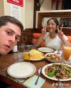 two people sitting at a table with food in front of them