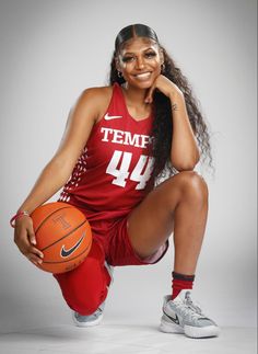 a female basketball player is posing for a photo with her foot up on the ball