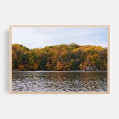 a lake surrounded by lots of trees with fall foliage on the hillside in the background