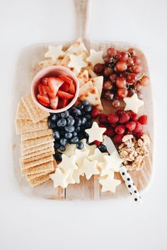 a platter with crackers, berries, strawberries, and cheese on it