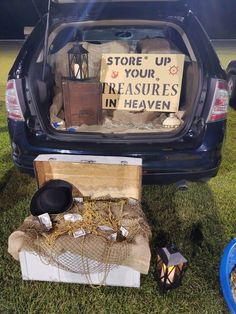 an open trunk filled with items sitting on top of a grass covered field next to a blue car