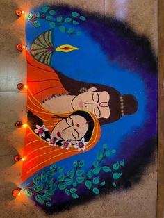 a painting on the ground with lights around it and an image of two people holding each other