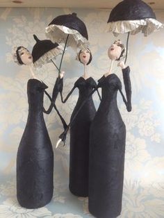 three black vases are holding umbrellas in the shape of people