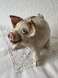 a small pig figurine sitting on top of a white doily covered table