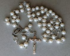 Sterling Silver.925 Freshwater Pearl handmade Rosary measures 24 and half inches long. Beautiful white Freshwater Pearls are 8mm. Each pearl is tied with .925 Sterling Silver wire.  Pearls are the Hail Mary prayers beads. Pearls are believed to signify innocence and faith. Pearls are known as a "stone of sincerity". Sterling Silver Crucifix Cross is one and half inches long. Virgin Mary Silver center piece is 3/4 inches. The Crystal Quartz beads are beautifully faceted and give a lovely delicate Elegant White Cross Rosary, White Crucifix Jewelry For Wedding, Elegant Silver Rosary For First Communion, Elegant White Wedding Rosary, Elegant White Rosary For Wedding, Silver Cross Rosary For Wedding, Elegant White Rosary For First Communion, Elegant White Rosary For Baptism, Elegant Silver Wedding Rosary