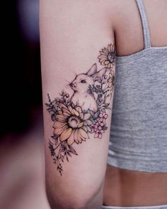 a woman's arm with flowers and a bunny tattoo on the left side of her arm