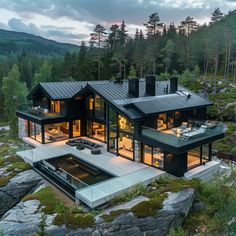 an aerial view of a house in the woods at dusk with lights on and hot tub