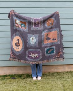 a person standing in front of a house holding up a blanket with pictures on it