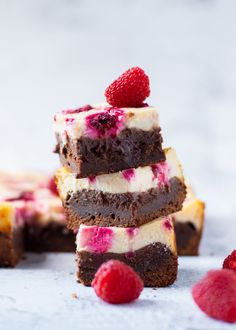 brownie cheesecake with raspberries on top is stacked high in the air