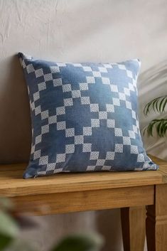 a blue pillow sitting on top of a wooden table next to a potted plant