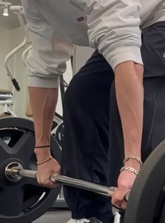 two people working out with barbells in a gym area, one holding the barbell