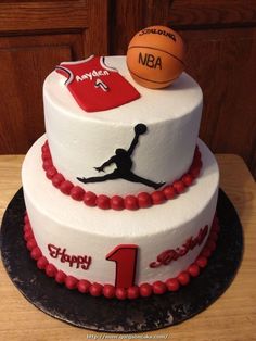 a three tiered cake with a basketball theme on the top and number one on the bottom