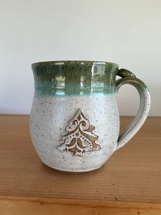 a white and green mug sitting on top of a wooden table