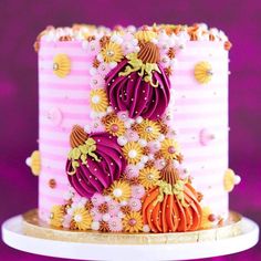 a pink and white cake decorated with flowers on a plate in front of a purple background