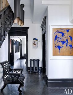 a black and white hallway with an art piece on the wall next to a wooden bench