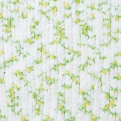 a close up view of a white fabric with green and yellow flowers