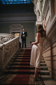 a woman in a white dress standing on stairs next to a man in a tuxedo