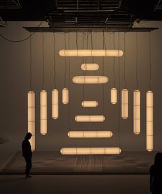 a man standing in front of a room filled with lights and suspended objects hanging from the ceiling