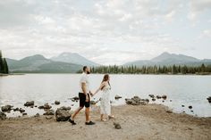 a man and woman holding hands by the water