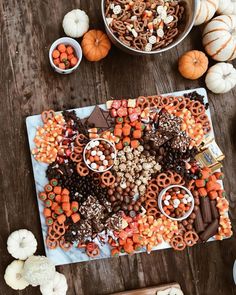 a wooden table topped with lots of candy and candies next to bowls of pumpkins