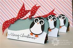 three penguins with bows on their heads are sitting in front of a christmas card box