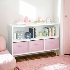 a white shelf with pink drawers in a child's room next to a bed