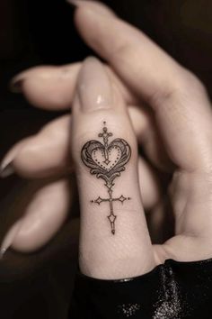 a woman's wrist tattoo with a cross and heart on the inside of it