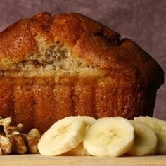 a loaf of bread with sliced bananas and walnuts next to it on a table