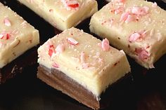 several pieces of cake sitting on top of a black plate covered in white frosting and pink sprinkles