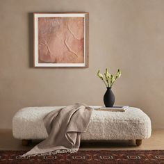 a living room with a couch, rug and painting on the wall above it that has flowers in a vase