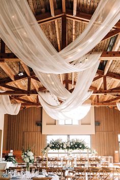 an indoor wedding venue with white draping on the ceiling