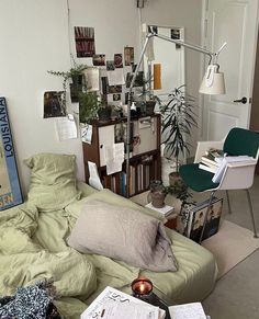 a room with a bed, chair and books on the floor next to a desk