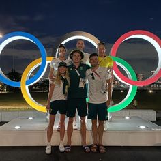 four people standing in front of the olympic rings