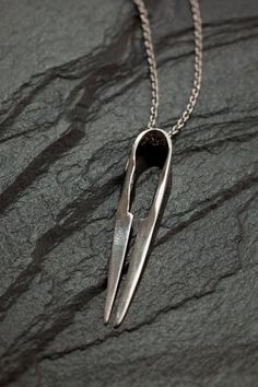 a pair of scissors hanging from a chain on top of a black stone surface,