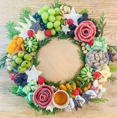 a wreath made out of fruits and vegetables on a wooden table with condiments