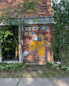 a brick building with graffiti on the side of it and trees in front of it