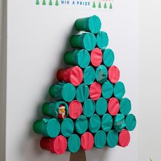 a christmas tree made out of rolled up toilet paper rolls is displayed on the wall