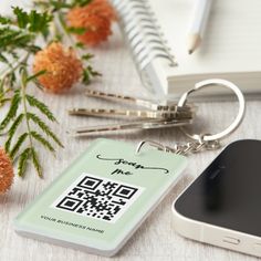 a qr code keychain sitting on top of a desk next to a cell phone