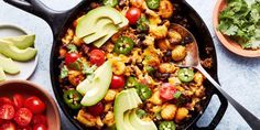 a skillet filled with vegetables and avocado on top of a blue table