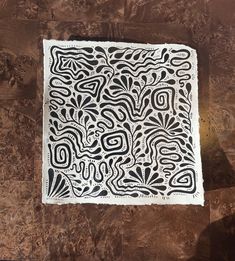 a piece of paper with black and white designs on it sitting on top of a wooden table