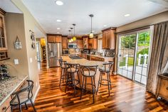 a kitchen with wooden floors and lots of counter space next to an open door that leads to a patio