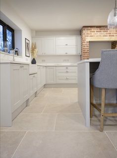 a kitchen with white cabinets and an island countertop next to a bar stool in the middle