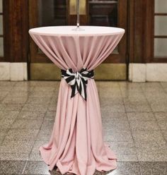 a table with a pink cloth draped over it and a candle on top, in front of an entrance