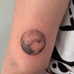 a woman's arm with a small tattoo of the moon and earth on it