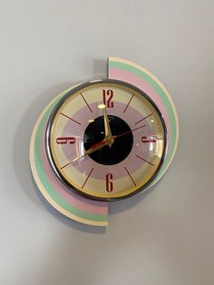 a clock that is on the side of a wall with numbers and colors around it