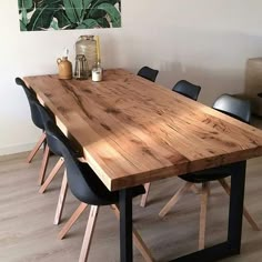 a wooden table with black chairs and a painting on the wall in the back ground